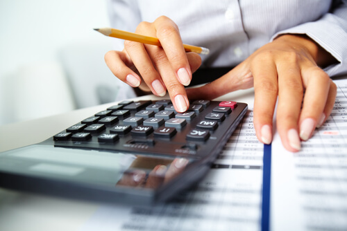 Manicured nails holding a pencil and calculator