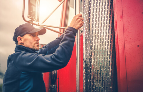 A truck driver getting into his red rig