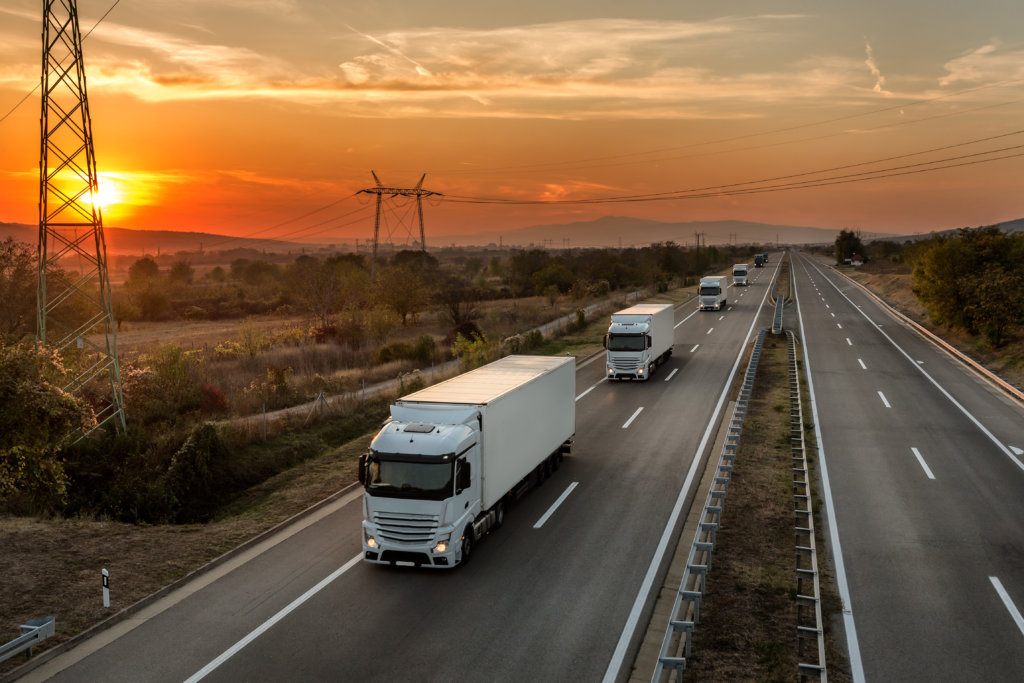 Fleet of transport trucks on highway showcasing the backbone of the vehicle shipping industry.