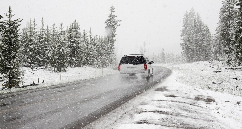 An SUV driving safely on a snow-covered road with winter tires.