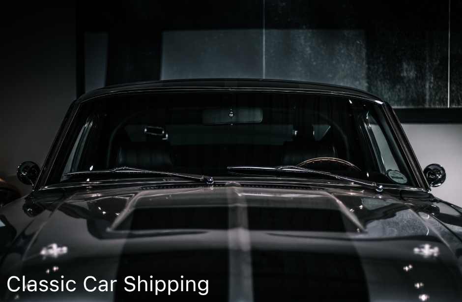 A vintage muscle car on a hydraulic lift inside an enclosed trailer